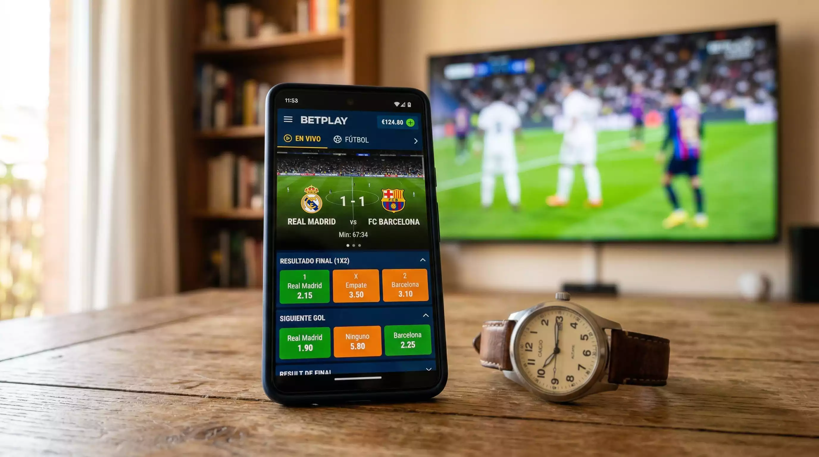 Teléfono móvil mostrando cuotas en vivo junto a un reloj marcando la hora del partido de la J-League