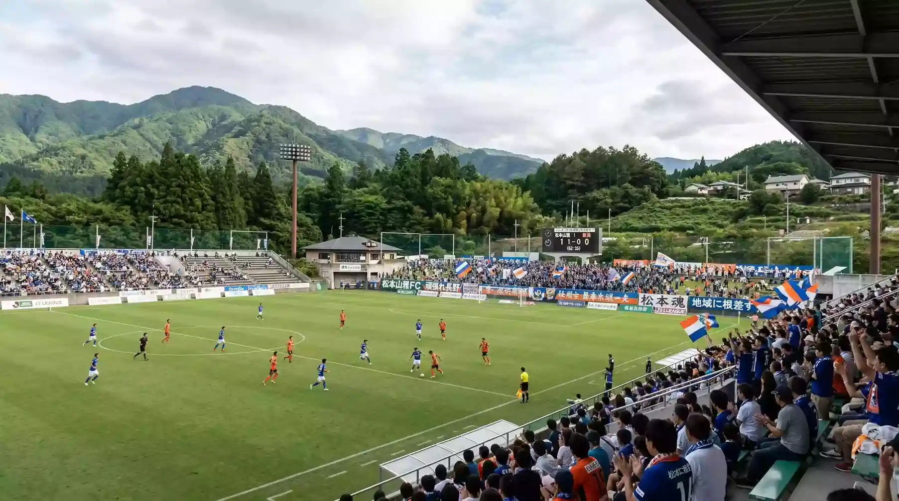 Partido de fútbol de la J2 League japonesa en un estadio regional con público en las gradas