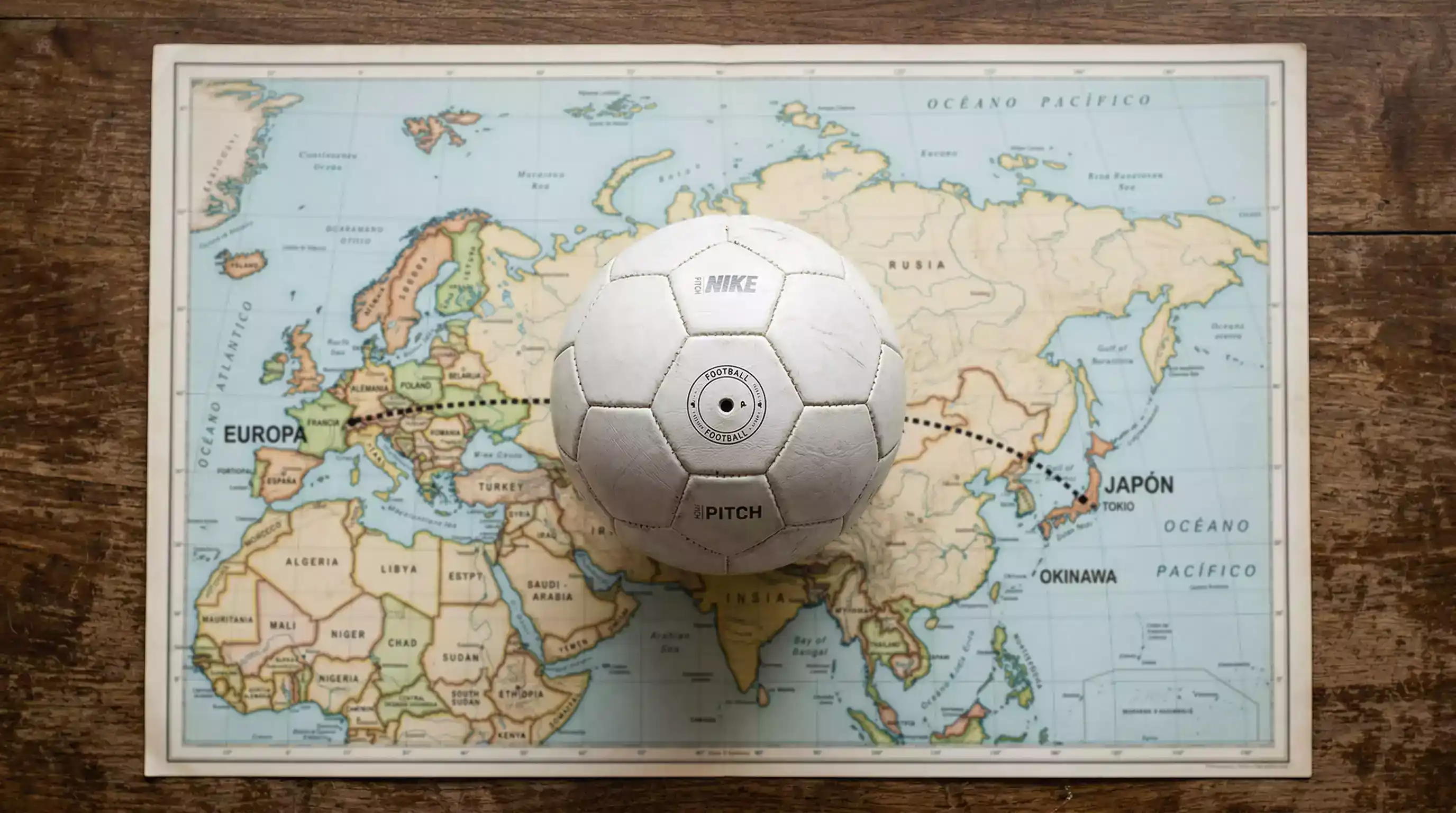 Balón de fútbol sobre un mapa que conecta Japón con Europa simbolizando la comparación entre ligas